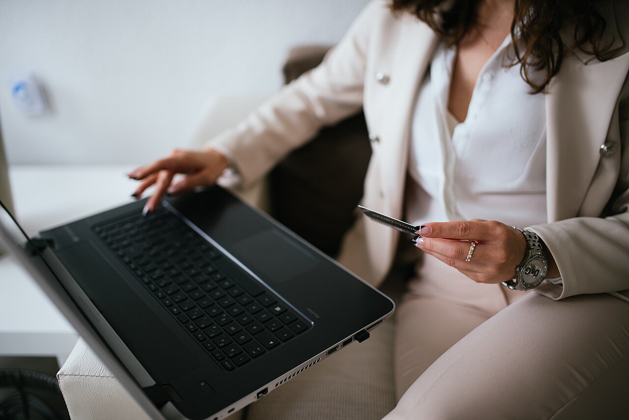 A person shopping online on a laptop while holding a credit card