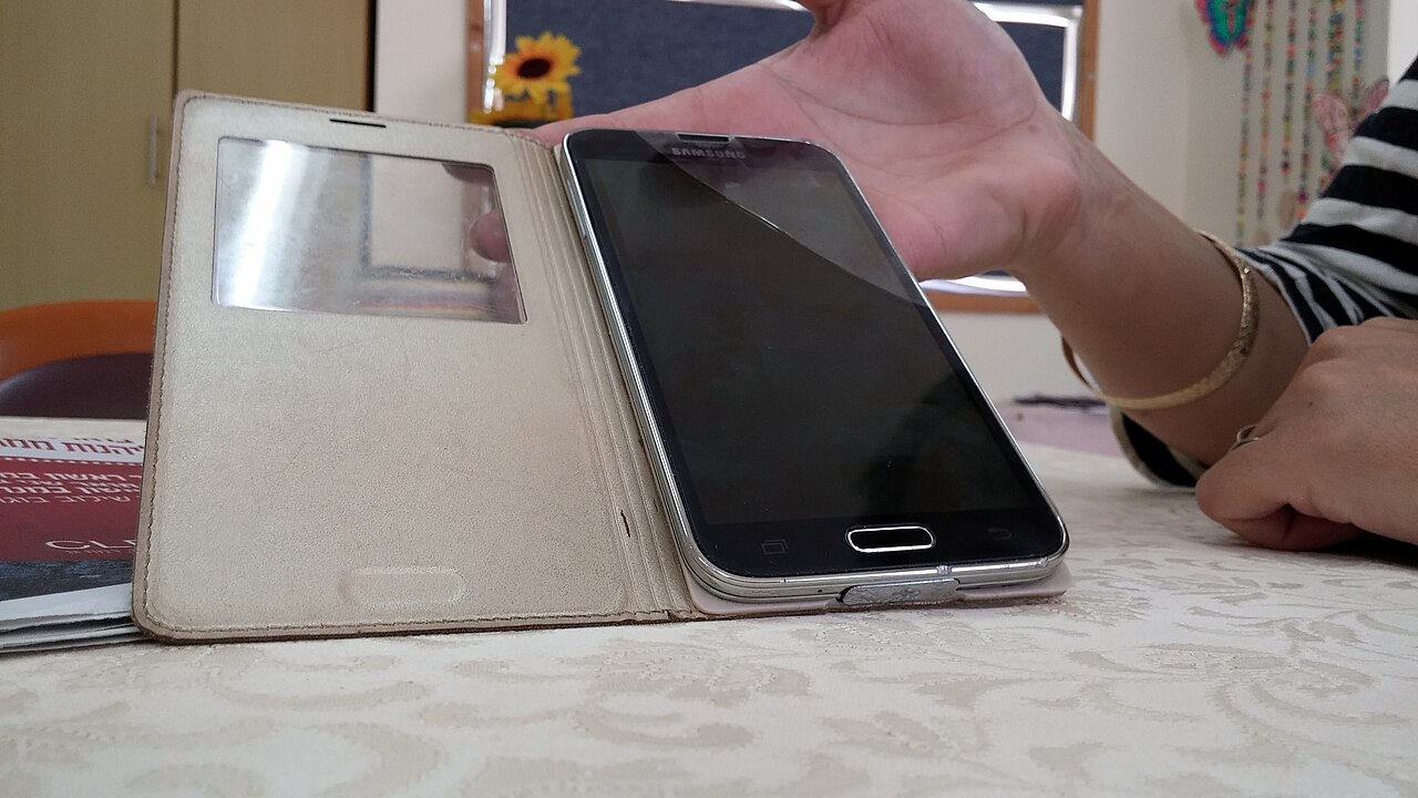 A smartphone in a flip cover held in one hand