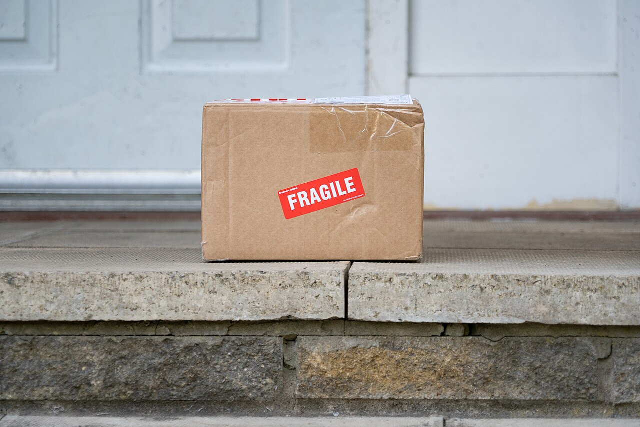 A cardboard box with a fragile sticker on a stone step