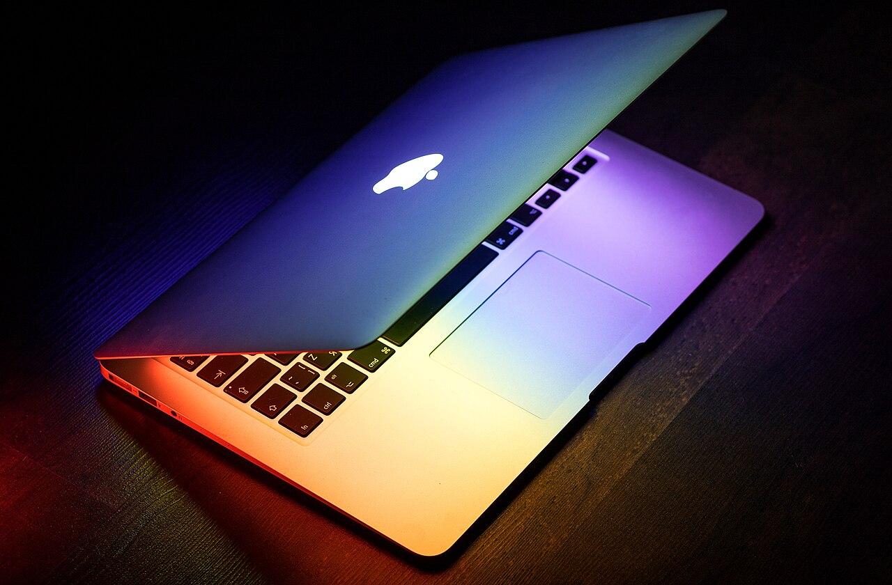 A MacBook Air lit by colourful light